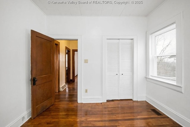 unfurnished bedroom featuring a closet and dark hardwood / wood-style floors