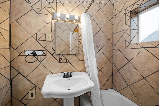 bathroom featuring shower / tub combo with curtain, sink, and tile walls