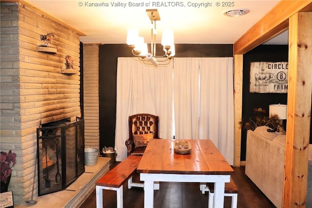 dining room featuring a fireplace, dark hardwood / wood-style flooring, and a notable chandelier