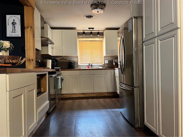 kitchen featuring appliances with stainless steel finishes, white cabinetry, sink, decorative backsplash, and dark wood-type flooring