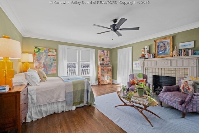 bedroom with crown molding, hardwood / wood-style flooring, a fireplace, and ceiling fan