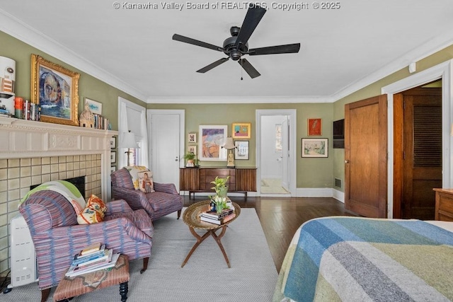 bedroom featuring ceiling fan, a fireplace, ornamental molding, and dark hardwood / wood-style floors