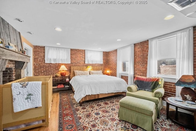 bedroom featuring brick wall and wood-type flooring