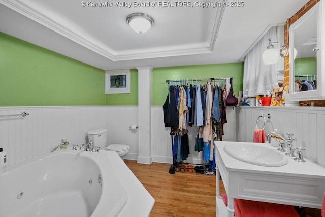 bathroom with hardwood / wood-style flooring, a raised ceiling, a tub to relax in, and toilet