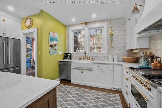 kitchen with stainless steel appliances, custom exhaust hood, sink, and white cabinetry