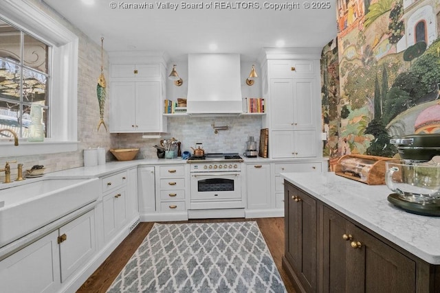 kitchen with high end white range, backsplash, light stone counters, dark hardwood / wood-style flooring, and custom exhaust hood