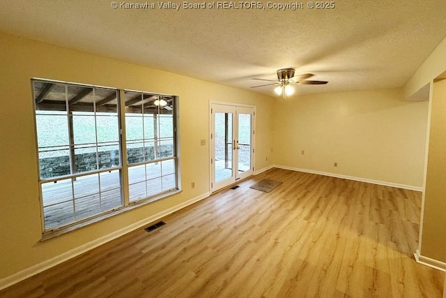 empty room with ceiling fan, light hardwood / wood-style flooring, french doors, and a textured ceiling