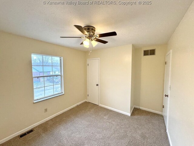 carpeted spare room with ceiling fan and a textured ceiling