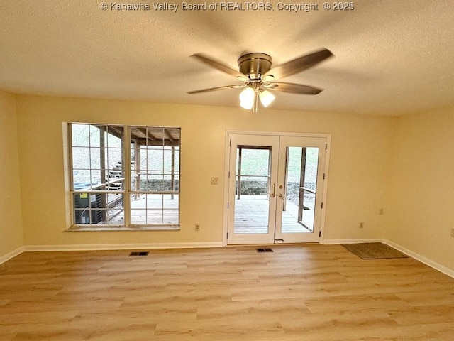 interior space featuring a wealth of natural light, light hardwood / wood-style flooring, a textured ceiling, and french doors