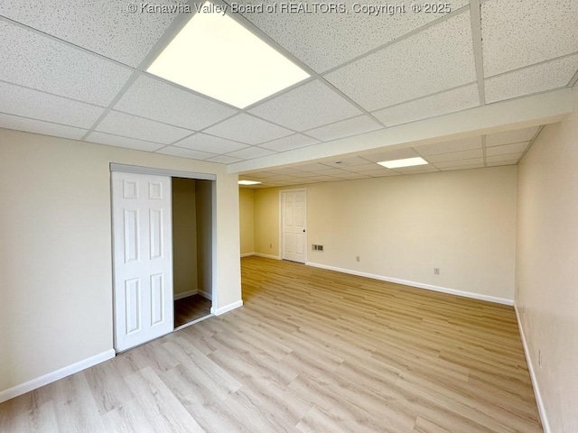 basement with a paneled ceiling and light wood-type flooring