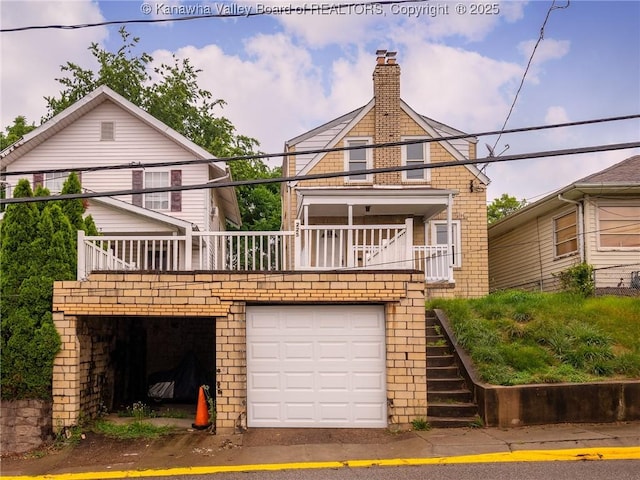 rear view of property featuring a balcony and a garage