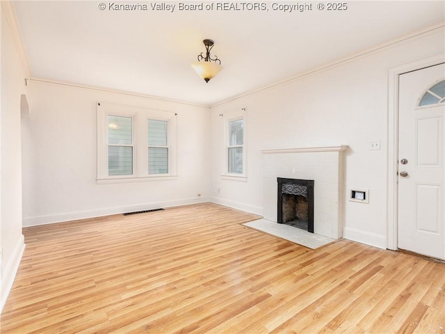 unfurnished living room featuring ornamental molding, a fireplace, and light wood-type flooring