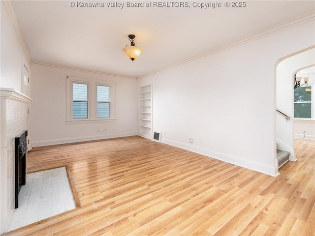 unfurnished living room with ornamental molding, built in features, and light hardwood / wood-style flooring