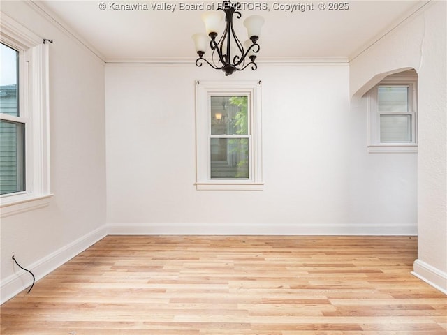 spare room with crown molding, plenty of natural light, and light wood-type flooring