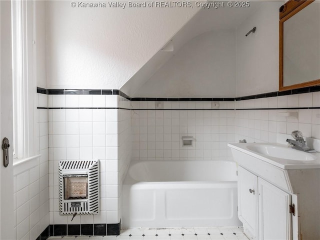 bathroom featuring vanity, heating unit, tile walls, and a tub to relax in