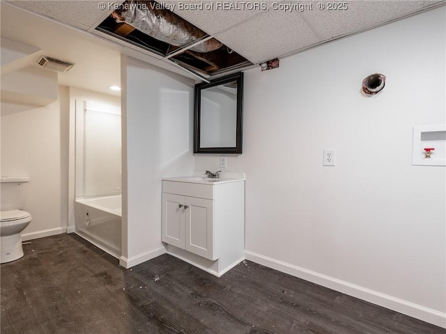 full bathroom featuring toilet, tub / shower combination, vanity, hardwood / wood-style floors, and a drop ceiling