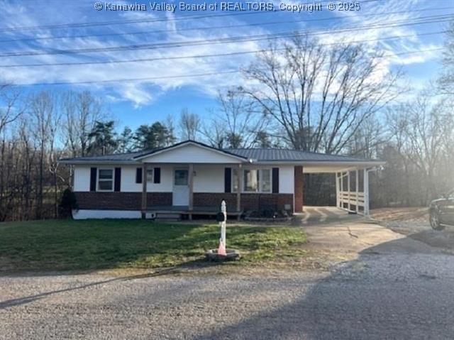 ranch-style home with a front lawn, a carport, and covered porch