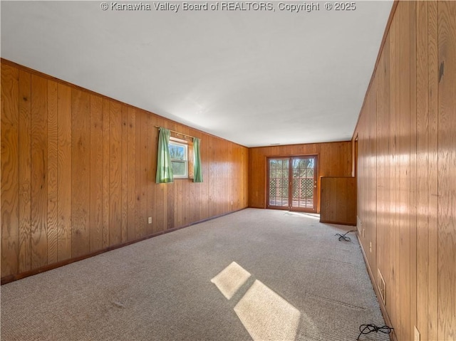 carpeted spare room with wooden walls