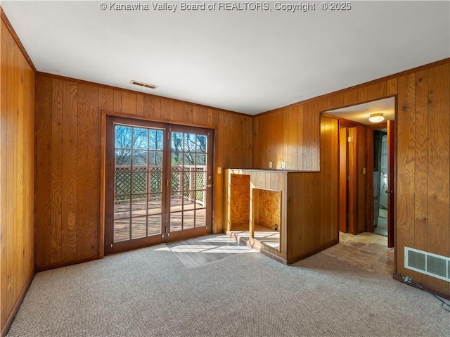 interior space with ornamental molding, light carpet, and wood walls