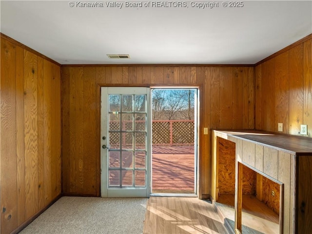 doorway featuring wooden walls and light colored carpet