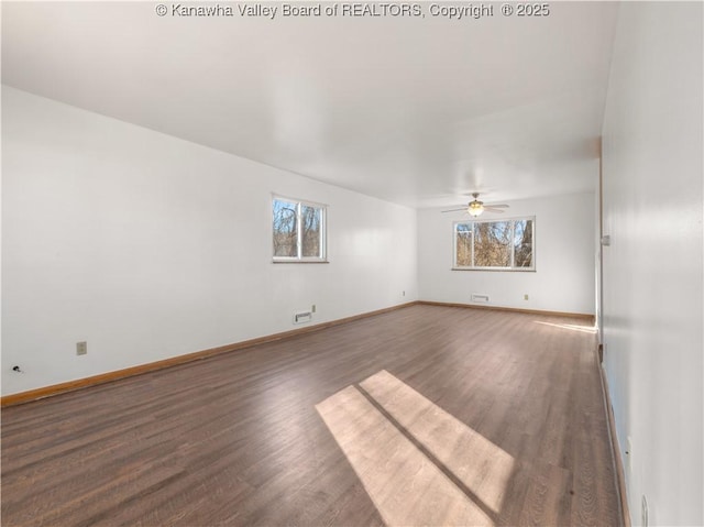 spare room featuring plenty of natural light, dark wood-type flooring, and ceiling fan