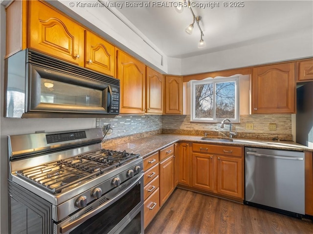 kitchen with appliances with stainless steel finishes, sink, backsplash, and dark hardwood / wood-style flooring