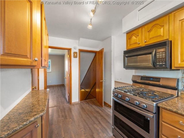 kitchen with range with two ovens, dark hardwood / wood-style floors, track lighting, and stone counters