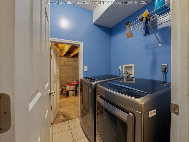 clothes washing area with washing machine and clothes dryer and light tile patterned floors