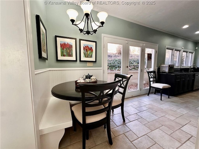 dining area featuring an inviting chandelier, sink, ornamental molding, and french doors