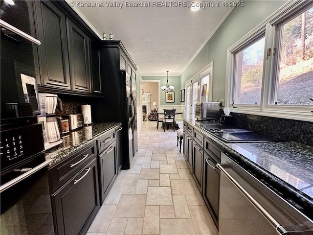 kitchen featuring an inviting chandelier, dark stone countertops, ornamental molding, black appliances, and decorative light fixtures