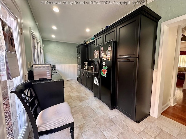 kitchen featuring ornamental molding, dark stone counters, and black appliances