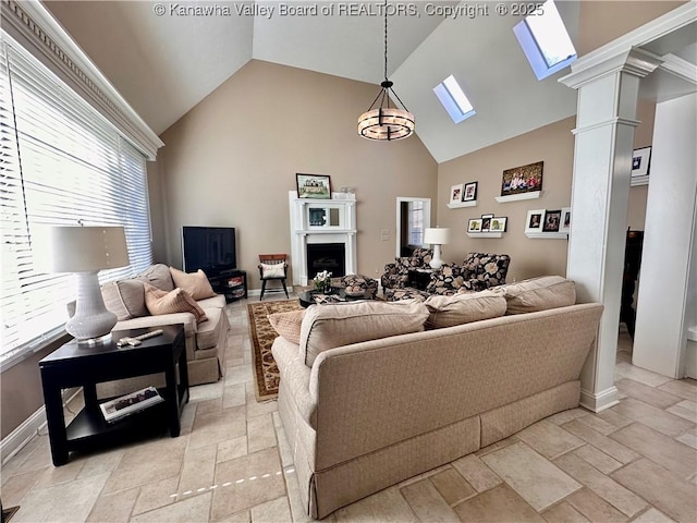 living room with ornate columns, high vaulted ceiling, and a skylight