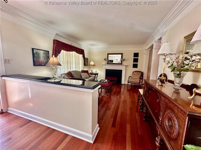 living room with decorative columns, ornamental molding, dark wood-type flooring, and a textured ceiling