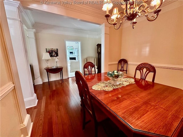 dining area featuring crown molding, dark hardwood / wood-style flooring, a chandelier, and ornate columns