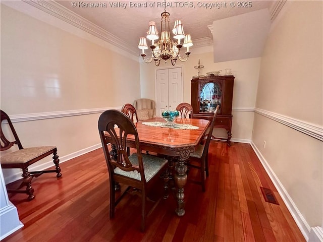 dining space featuring crown molding, dark wood-type flooring, and an inviting chandelier