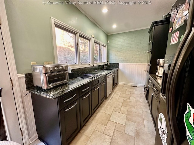 kitchen featuring stainless steel appliances, ornamental molding, sink, and dark stone countertops