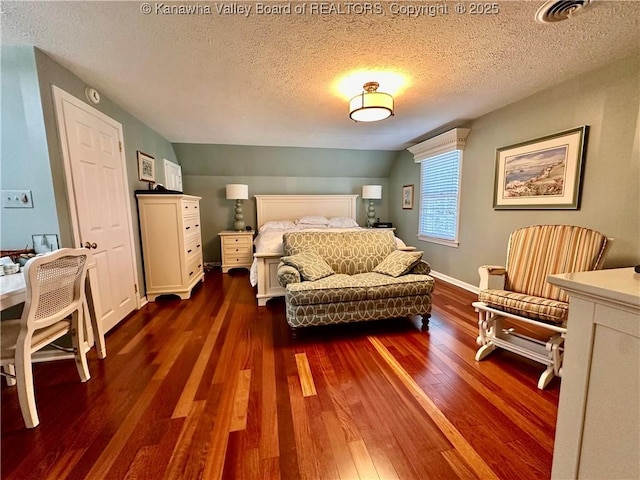 bedroom with vaulted ceiling, a textured ceiling, and dark hardwood / wood-style flooring