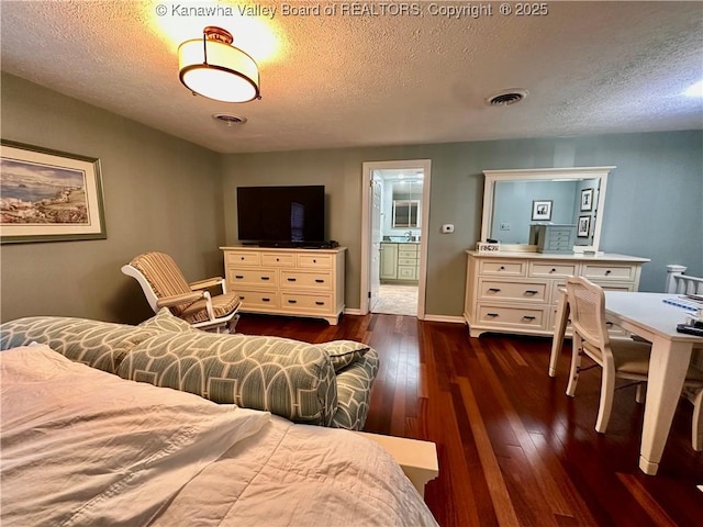 bedroom featuring ensuite bathroom, dark hardwood / wood-style flooring, and a textured ceiling