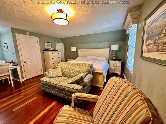 bedroom featuring vaulted ceiling, dark wood-type flooring, and a textured ceiling