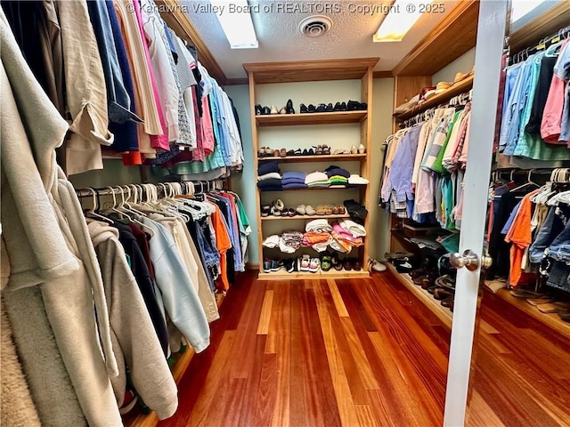 walk in closet with hardwood / wood-style flooring