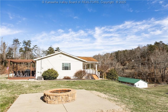 rear view of house with a yard, a patio area, and a fire pit