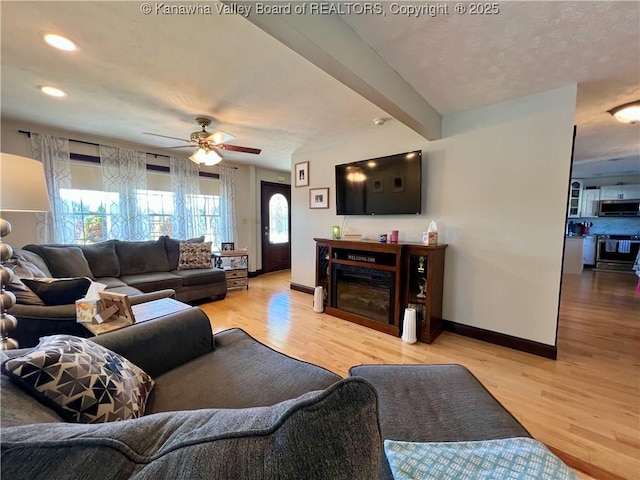 living room featuring beamed ceiling, ceiling fan, and light hardwood / wood-style flooring