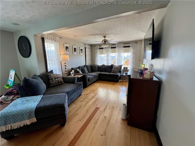 living room with ceiling fan, a textured ceiling, light hardwood / wood-style floors, and a healthy amount of sunlight