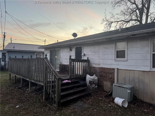 back house at dusk with a wooden deck and central air condition unit