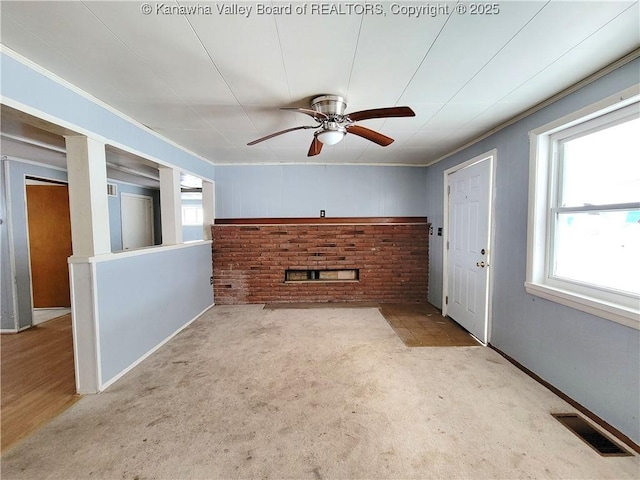 unfurnished living room featuring ornamental molding, light colored carpet, a fireplace, and ceiling fan