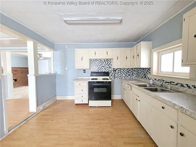 kitchen with sink, gas range, light hardwood / wood-style flooring, and backsplash