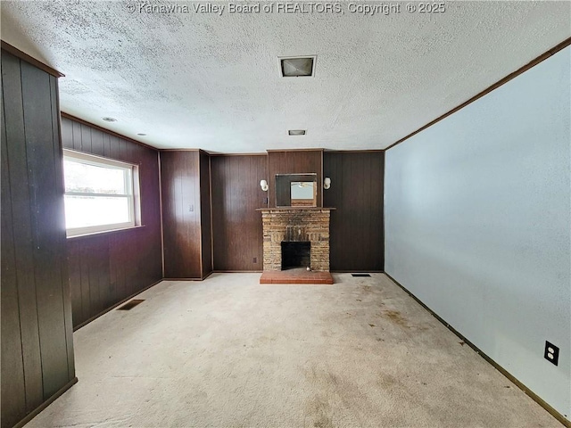 unfurnished living room with light colored carpet, wooden walls, and a textured ceiling