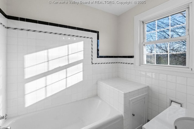 bathroom with vanity, tile walls, and a bathtub