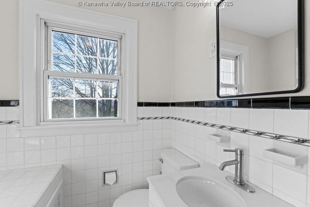 bathroom with vanity, toilet, and tile walls