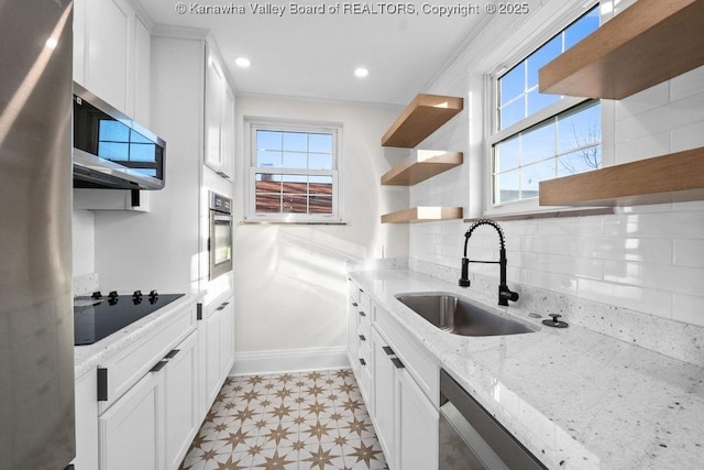 kitchen with appliances with stainless steel finishes, tasteful backsplash, white cabinetry, sink, and light stone counters